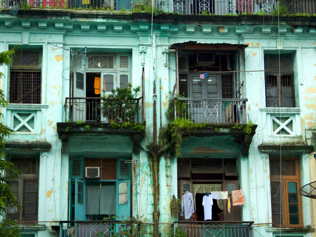 In this image I can see few trees which are green in color and a building which is also green in...
