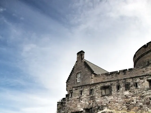 This is a picture of a castle on a hill. In the foreground of the picture there are people on the...