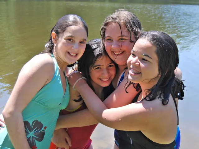 In the foreground of the picture there are group of girls, behind them there is a water body.