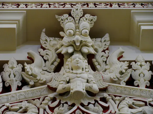 The picture consists of a sculpture on a building. At the top there are floral designs.